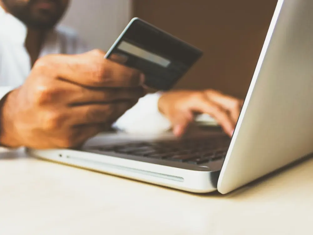 Persoană care plătește cu cardul o comandă făcută online de pe laptop